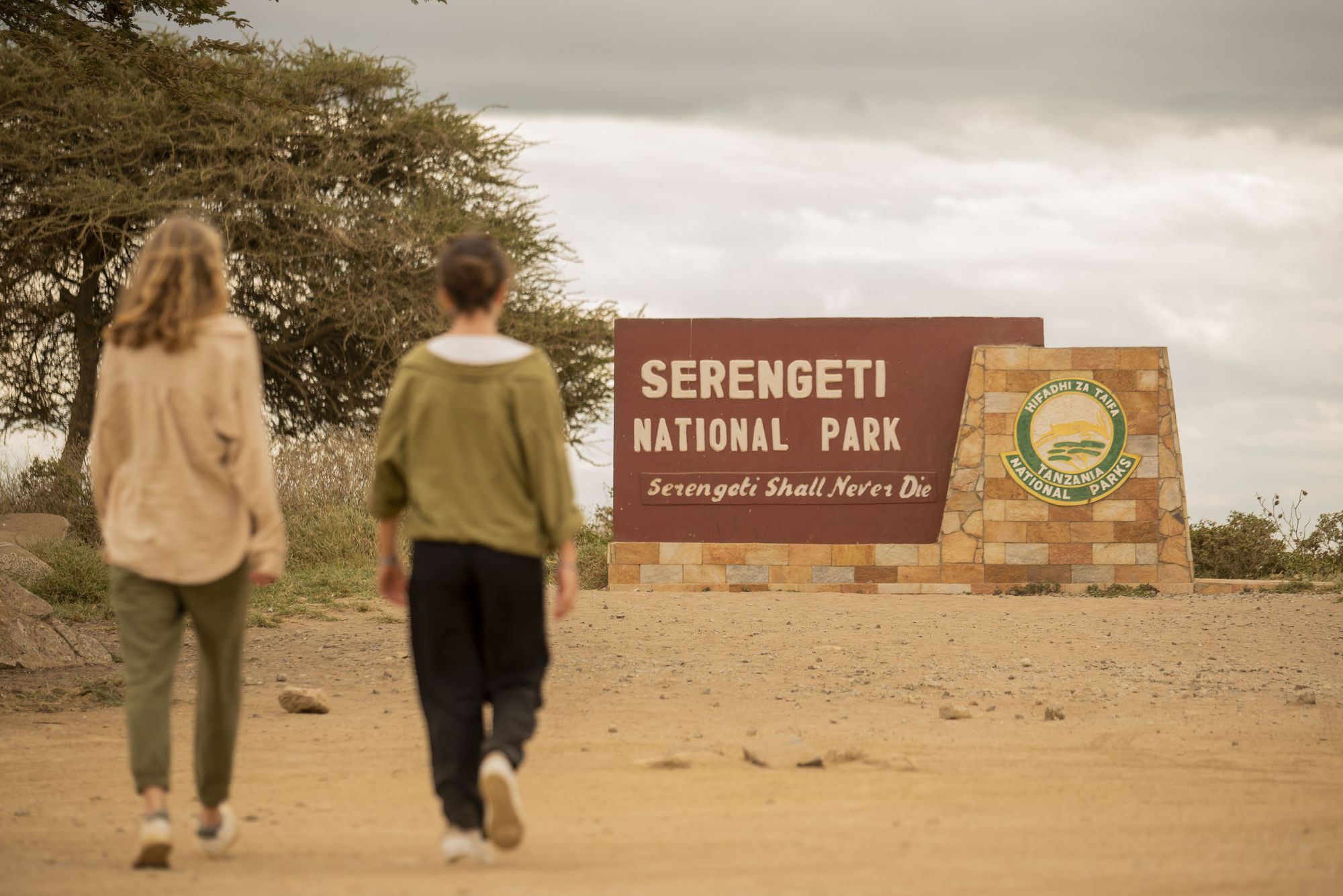 Two travellers walking up to the Serengeti National Park gate